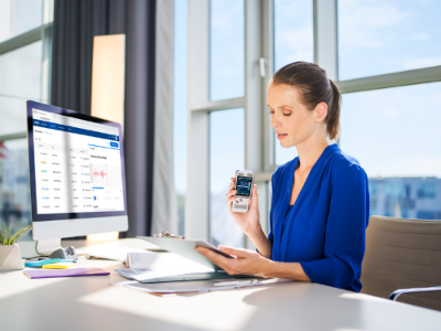 Woman working at a desk with a computer and smartphone in an office setting