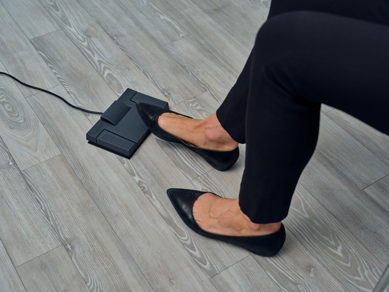 Person wearing black shoes with her foot on OM System RS-28N foot pedal
