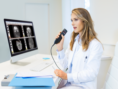 Doctor analyzing medical images on a computer screen in a clinical setting and talking into a Philips SpeechMike.