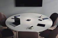 Round table with laptop and three smart phones around the table, cops of coffee and notebooks by the smartphones and a JabraSpeak 750 in the  centre of the table