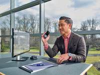 Man sitting at desk dictating into OM System DS-2700 dictaphone