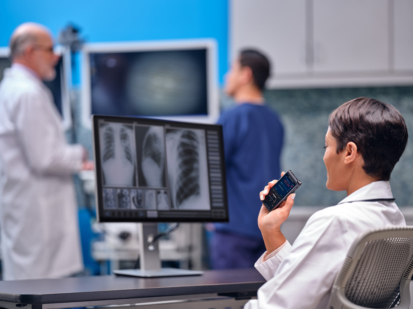 Radiologist recording notes, while examining x-rays, on OM System DS-9100 dictaphone