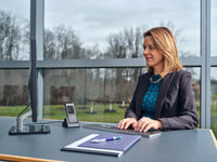 Woman sitting at a desk, using  OM System DS-9100 dictaphone for hands free dictation