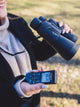 OM System WS-883 digital voice recorder being used in the field by a person with binoculars