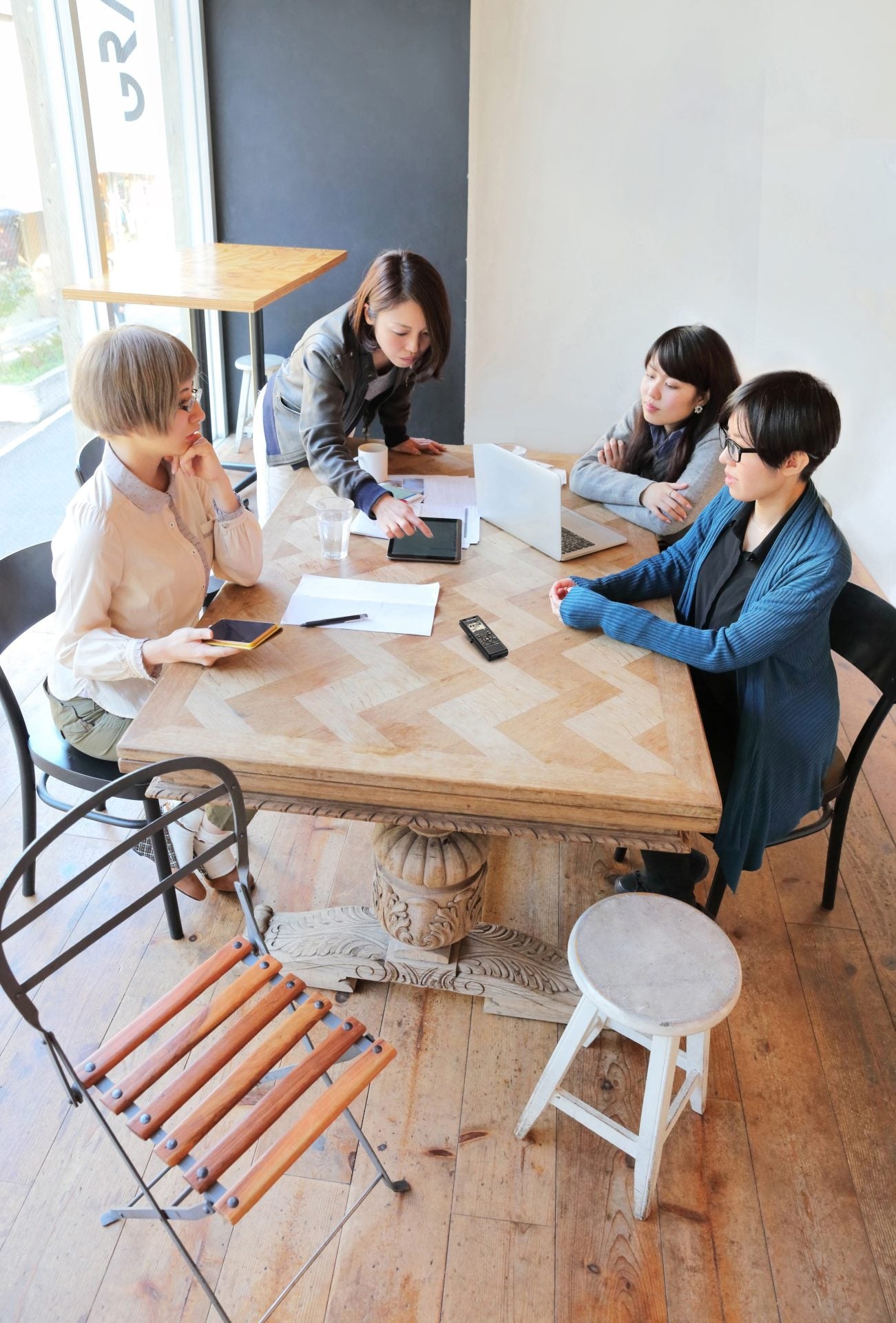 Four people sitting around a table, recording a meeting with OM System WS-883 digital voice recorder