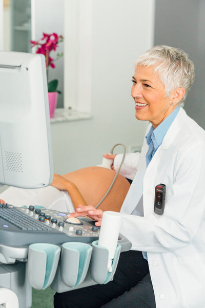 Doctor using Philips SpeechMike Ambient, clipped to her pocket, to record her voice while conducting ultrasound on a patient.