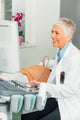 Doctor using Philips SpeechMike Ambient, clipped to her pocket, to record her voice while conducting ultrasound on a patient.